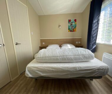 Chambre avec lit double et fenêtre dans le mobil home du camping de la falaise à Equihen-Plage