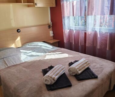 Chambre avec lit double et serviettes dans le mobil home au bord du lac de Foix