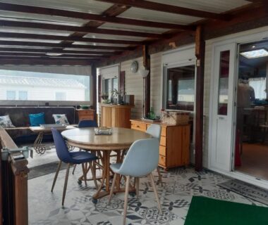 Espace détente couvert avec table et canapés du mobil home au bord du lac de Foix