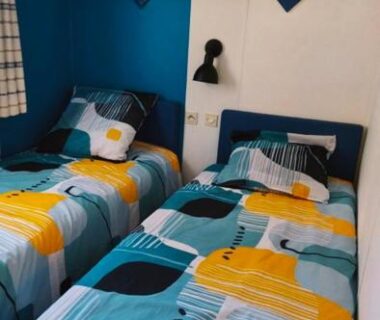 Intérieur chambre avec deux lits et étagère de jeux dans le mobil-home au camping L'Oasis Village Montana Parc
