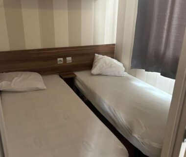 Chambre avec deux lits séparés et petite étagère dans le Mobil home au Castellas Marseillan