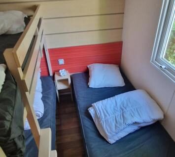 Chambre avec lits superposés et lit simple près de la fenêtre dans le mobil-home avec grande terrasse