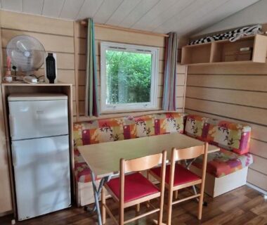 Coin repas intérieur avec banquette et réfrigérateur dans le Mobil-home avec grande terrasse