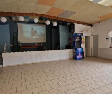 Salle d'animation avec scène et sol carrelé au camping près du mobil-home avec grande terrasse