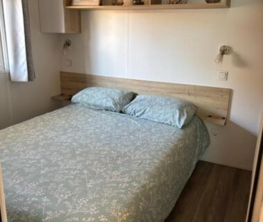 Intérieur chambre avec lit double et étagères dans le mobil home du Camping Les Viviers