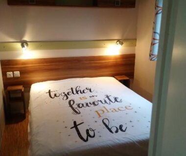 Chambre avec lit double et étagères dans le Mobil home camping 4 étoile