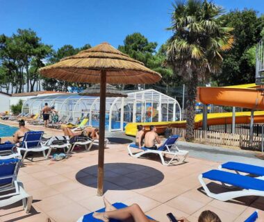 Espace piscine extérieur avec parasols transats et toboggan au Mobil home camping 4 étoile