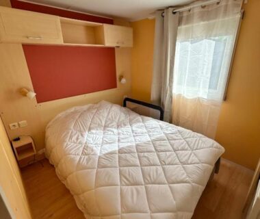 Chambre avec lit double rangement et fenêtre dans le mobil home camping Lalande Mimizan