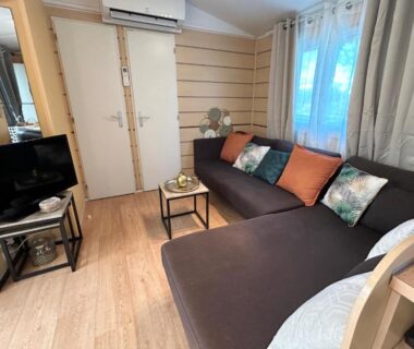 Salon avec canapé et télévision du mobil home camping Lalande Mimizan