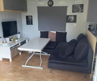 Salon avec canapé, table et télévision dans le mobil home camping Paradis du Quinquis