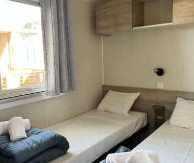Intérieur du mobil-home avec deux lits et fenêtre dans le mobil-home camping la Marine 4 étoiles le Grau du roi
