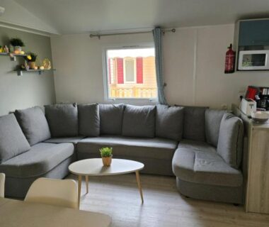 Intérieur salon avec canapé d'angle et table basse dans le Mobil home camping les Viviers 8 personnes