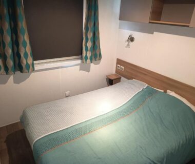 Chambre avec lit double rideaux et lampe du Mobil-home camping les sables du midi