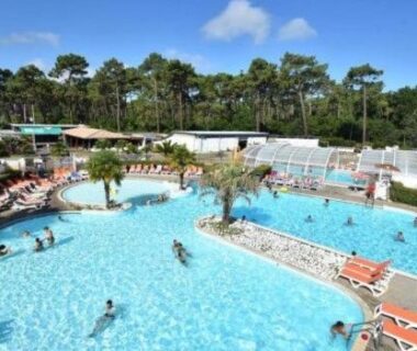 Piscine extérieure avec transats et palmiers au Mobil home camping luxe 4 étoiles