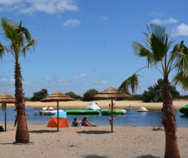 Plage de sable avec parasols palmiers et pédalos au Mobil home camping luxe 4 étoiles
