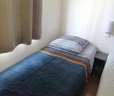 Chambre intérieure avec lit simple table de chevet et rideau dans le Mobil home chez Alain120