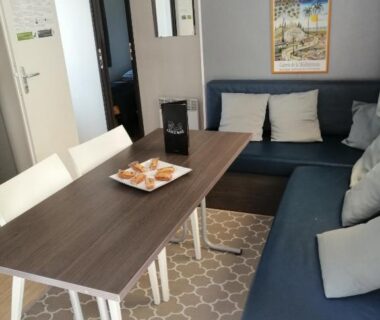 Intérieur avec coin repas table chaises et canapé dans le mobil home chez Alain120