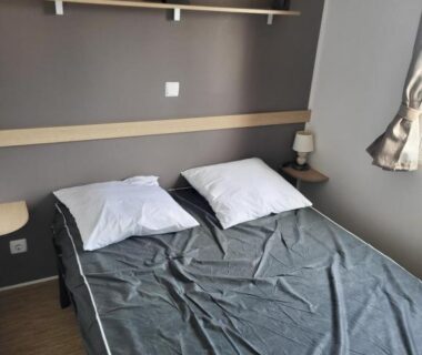 Chambre avec lit double lampe et étagère dans le mobil-home chez MG