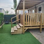 Terrasse couverte en bois avec marches et pelouse synthétique au mobil-home chez MG