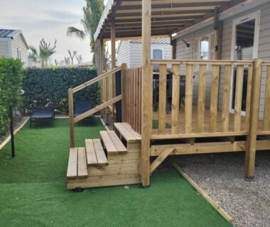 Terrasse couverte en bois avec marches et pelouse synthétique au mobil-home chez MG