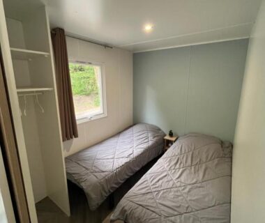 Chambre avec deux lits simples et fenêtre dans le Mobil home climatisé
