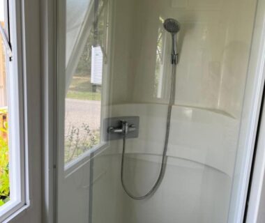 Salle de douche avec cabine vitrée et pommeau dans le mobil home climatisé