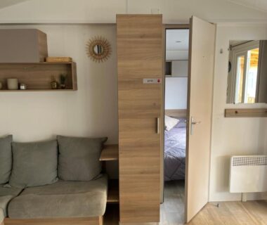Salon avec canapé et chambre ouverte dans le mobil home climatisé