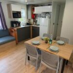 Intérieur avec canapé table à manger et kitchenette du Mobil-home climatisé 6 personnes