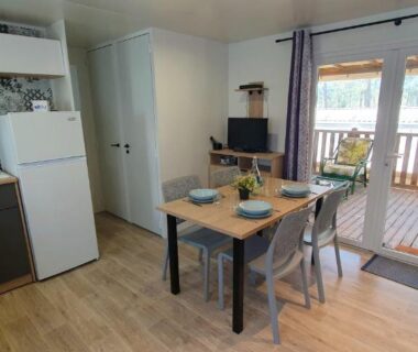 Séjour avec coin cuisine et table donnant sur la terrasse du Mobil-home climatisé 6 personnes