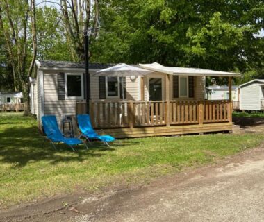 Terrasse en bois avec chaises bleues sur pelouse du Mobil home climatisé 6 personnes au camping Tohapi Boofzheim
