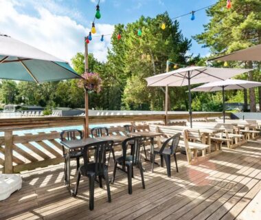Terrasse en bois avec piscine et parasols du mobil-home climatisé à 5 min de la mer charmant