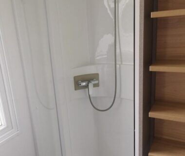 Douche cabine vitrée avec pommeau et étagères dans le mobil home climatisé chez Mickaël et Laëtitia
