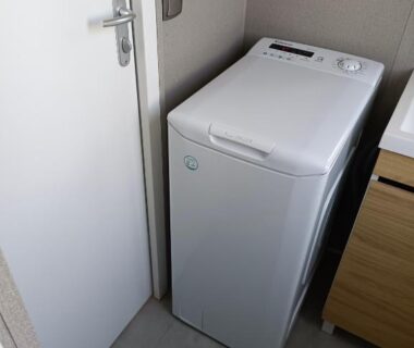 Coin buanderie avec lave linge top dans le mobil home climatisé chez Mickaël et Laëtitia