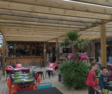 Terrasse en bois couverte avec chaises colorées et bar du Mobil home climatisé chez Mickaël et Laëtitia