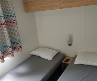 Intérieur chambre avec deux lits et rangement dans le mobil home climatisé chez Mickaël et Laëtitia