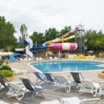 Piscine extérieure avec toboggans et transats au mobil-home climatisé proche lac du camping 4 étoiles piscine chauffée