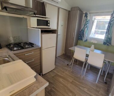 Intérieur avec coin cuisine et table dans le mobil-home climatisé proche lac camping 4 étoiles piscine chauffée