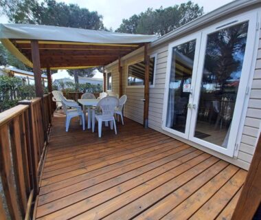 Terrasse en bois avec table et chaises dans le mobil-home climatisé 3 chambres du camping La Presqu'île du Barcarès