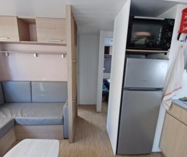 Intérieur avec coin salon et kitchenette du mobil home climatisé 3 chambres à La Presqu'île du Barcares