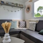 Intérieur coin salon avec banquette d'angle coussins et vase du Mobil-home confort Camping 4 étoiles Clim et plage