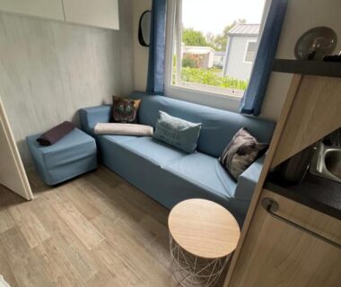 Intérieur salon avec banquette et fenêtre du mobil home confort XL au camping HOMAIR la pommeraie