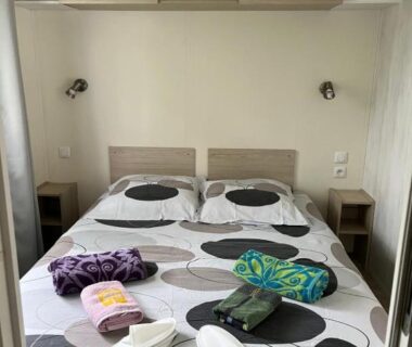 Chambre avec lit double et serviettes dans le mobil home confort XL du camping HOMAIR la pommeraie