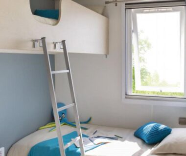 Intérieur chambre avec lits superposés, fenêtre et coussins dans le Mobil-home confortable – 4 pers. – API-1-52-2731