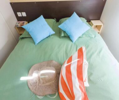 Chambre avec lit double et coussins dans le mobil-home confortable avec terrasse à Pezuls API-1-52-683