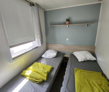 Chambre avec deux lits et étagère dans le mobil-home cosy 166