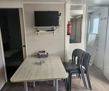 Séjour avec table chaises et télévision dans le mobil-home cosy 166