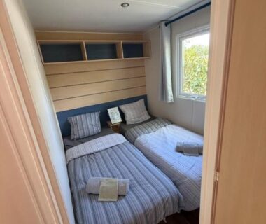 Chambre avec deux lits simples et serviettes pliées dans le mobil-home au Camping domaines des iscles