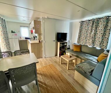 Intérieur séjour avec salon et kitchenette du mobil-home cosy climatisé 5 pers Terrasse couverte Plage des Casernes à 800m