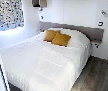 Chambre avec lit double et coussins jaunes dans Mobil-home cosy climatisé 5 pers – Terrasse couverte – Plage des Casernes