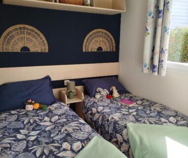 Chambre avec deux lits simples et rangements dans le Mobil home cosy dans camping 4 étoiles